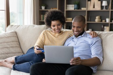 Mutlu genç Afrikalı Amerikalı aile mallar için internetten ödeme yapıyor..