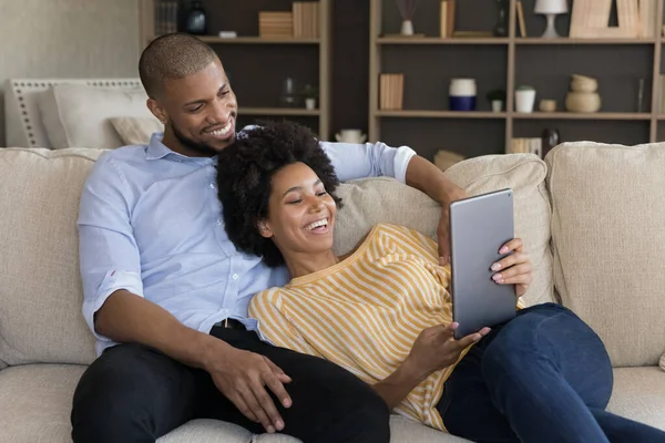 Relajado sonriente millennial mezcla de raza pareja usando tableta. —  Fotos de Stock