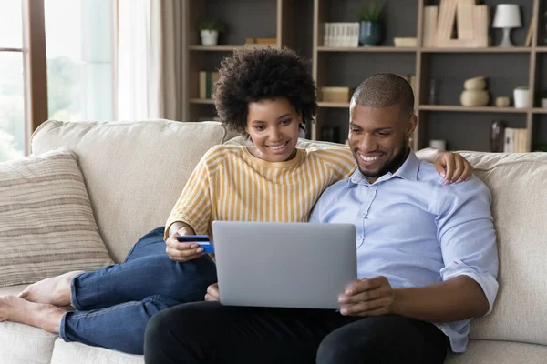 Счастливая молодая африканская семейная пара платит за товары онлайн. — стоковое фото
