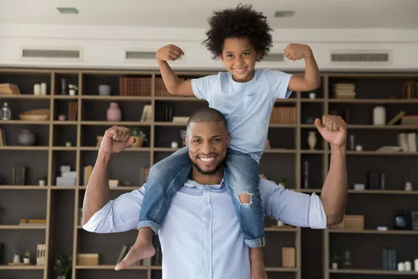 Feliz família afro-americana mostrando músculos em casa. — Fotografia de Stock