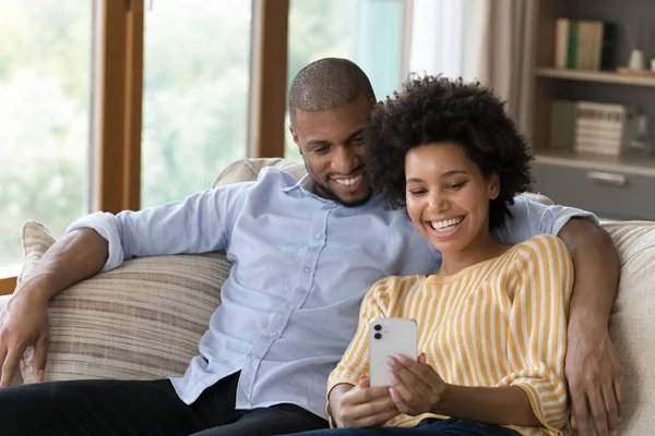 Afectuosa pareja de jóvenes afroamericanos de la familia usando el teléfono celular. —  Fotos de Stock