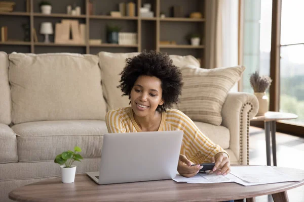 Feliz joven afroamericana mujer calculando los gastos domésticos. — Foto de Stock