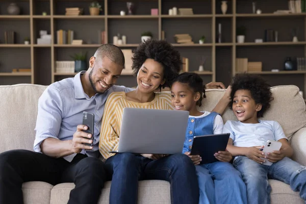 Heureuse famille afro-américaine utilisant différents gadgets. — Photo