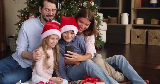 I genitori sorridenti bambini preadolescenti trascorrono le vacanze di Natale insieme usando il telefono — Video Stock