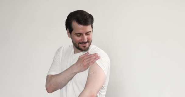 Homem sorridente mostrando bandagem adesiva no ombro após a vacinação — Vídeo de Stock