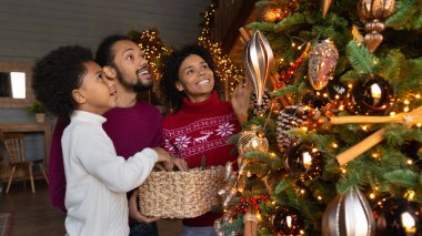 Çift ırklı aile manzarası Noel ağacını süslüyor
