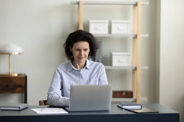 Konzentrierte Geschäftsfrau mittleren Alters arbeitet am Computer. — Stockfoto