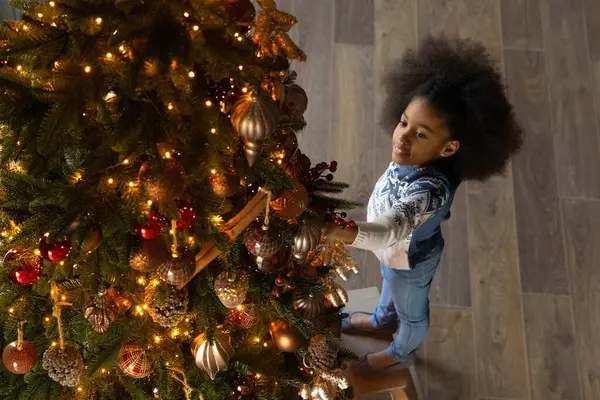 Piccola ragazza biraciale decorare l'albero di Natale a casa — Foto Stock