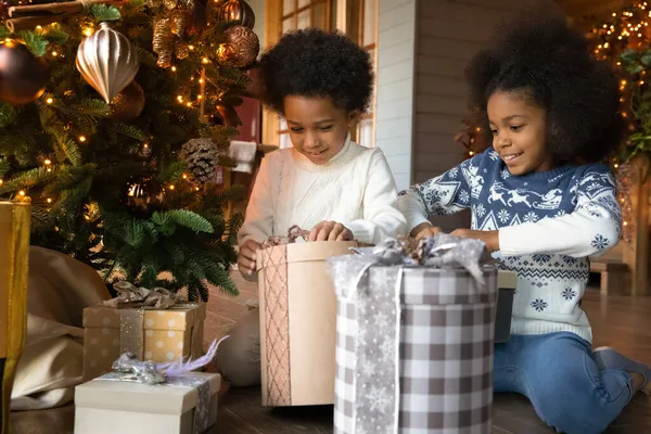 Crianças biraciais excitadas desembalam presentes de Natal em casa — Fotografia de Stock