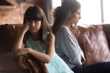 Kızgın inatçı kız ve üzgün anne kanepede oturuyor.