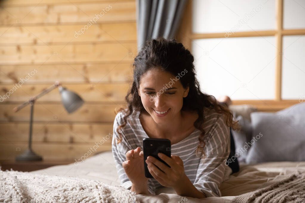 Smiling female smartphone user reading message with good news