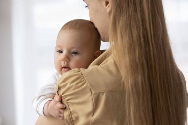 Arkadan bakan sevgi dolu genç bir anne kucağında sevimli bir bebek