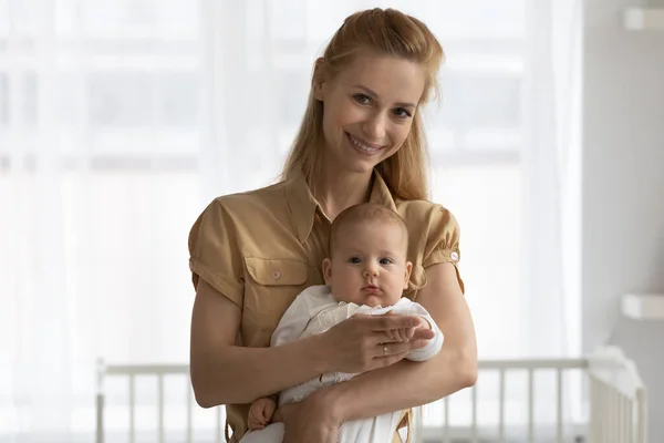Head shot portrait of smiling young mother holding baby — Stock Photo, Image