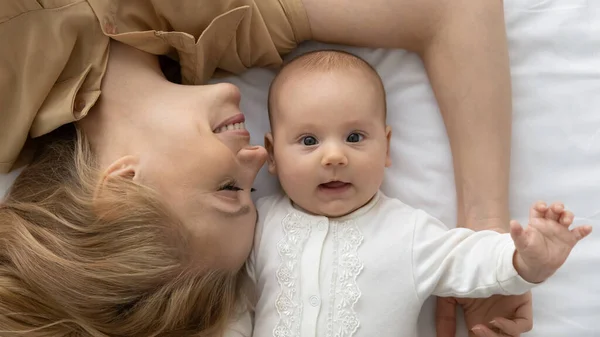 Top widok portret dziecka i młodej matki leżącej na łóżku — Zdjęcie stockowe