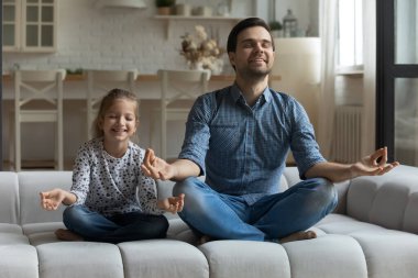 Mutlu küçük kız ve genç baba yoga yapıyor..