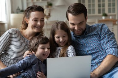 Evde bilgisayar kullanan mutlu ebeveynler ve küçük çocuklar..