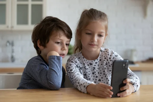 Glada söta små barn som leker mobiltelefon hemma. — Stockfoto
