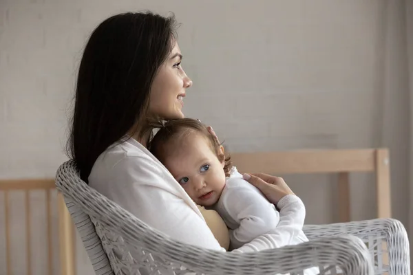 Profiel van lachende moeder knuffelende kleine dochter, zittend in stoel — Stockfoto