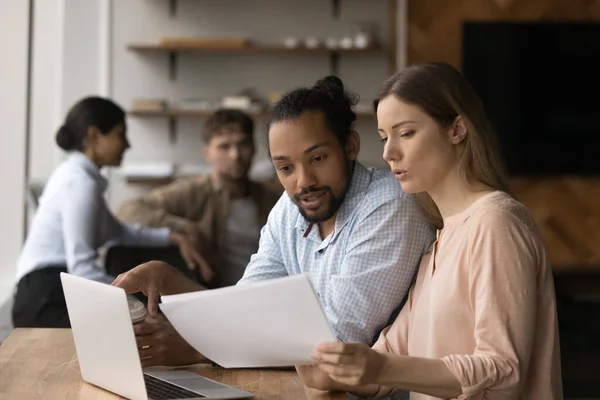 Concentrated mixed race colleagues analyzing paper report. — Stock Photo, Image