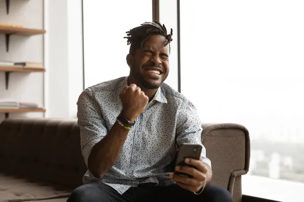 Overjoyed young mixed race man celebrating internet success. — Stock Photo, Image