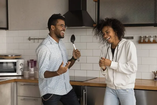 Heureux jeune couple afro-américain chantant des chansons dans la cuisine. — Photo