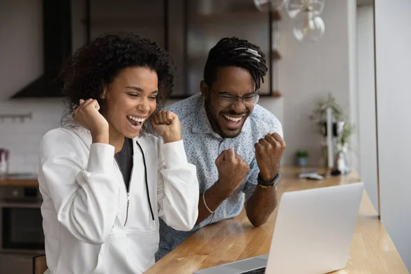 Überglücklich lachendes junges afrikanisches Paar feiert Interneterfolg. — Stockfoto