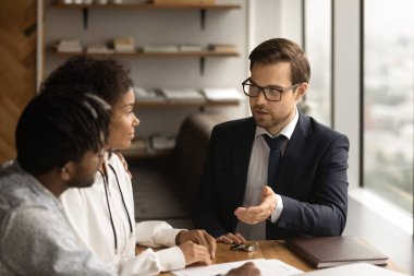 Ofis toplantısında yetenekli genç erkek emlakçı müşterilere danışıyor..