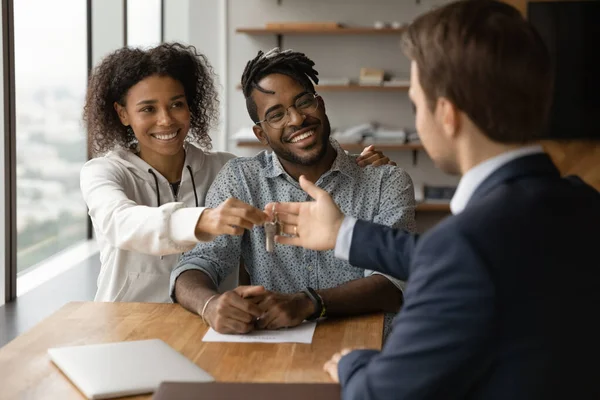 Gelukkig jong gemengd ras familie paar nemen sleutels van makelaar. — Stockfoto