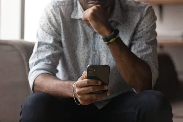 Pensativo joven africano mestizo hombre de raza utilizando el teléfono celular. —  Fotos de Stock