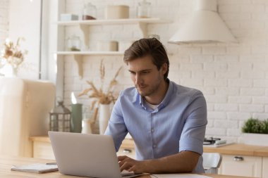 Yakışıklı, düşünceli adam. Masaya otur ve dizüstü bilgisayarla çalış.