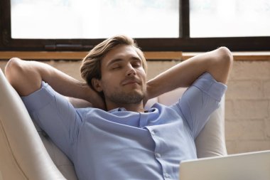 Huzurlu adam rahat rahat dizüstü bilgisayarla koltuğa yaslanıyor.