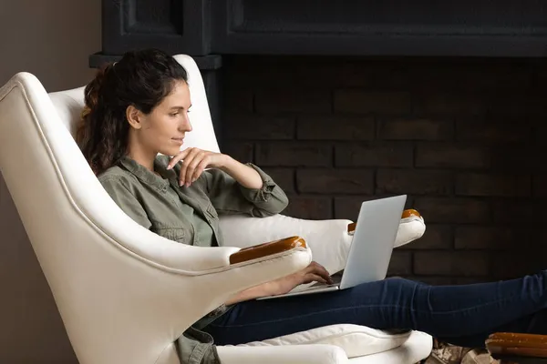 Kvinnan sitter i fåtölj köpa på internet användning laptop — Stockfoto