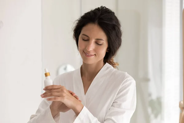Kobieta w szlafroku nakłada serum na suchą skórę dłoni — Zdjęcie stockowe
