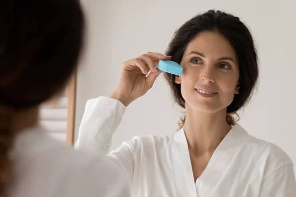 Mulher detém esponja triângulo aplicando fundação creme na pele — Fotografia de Stock