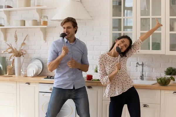 Lively attraente giovane coppia che canta ballare in cucina — Foto Stock