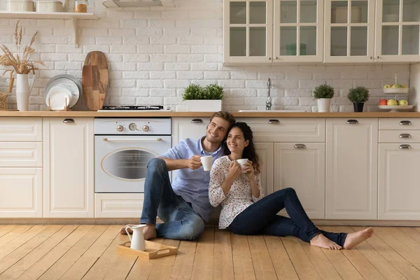 Couple se détendre sur le sol dans la cuisine tient tasses boire du thé — Photo