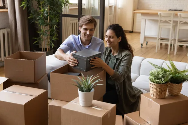 Beautiful couple taking out belongings from boxes at relocation day — Stock Photo, Image