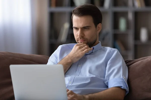 Joven reflexivo mirando la pantalla del ordenador portátil . — Foto de Stock