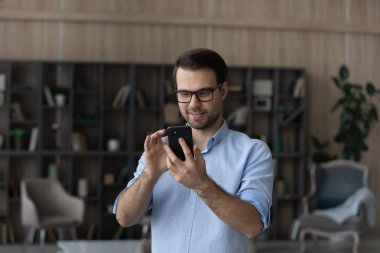 Gülümseyen milenyum işadamı ofiste telefonla konuşuyor..