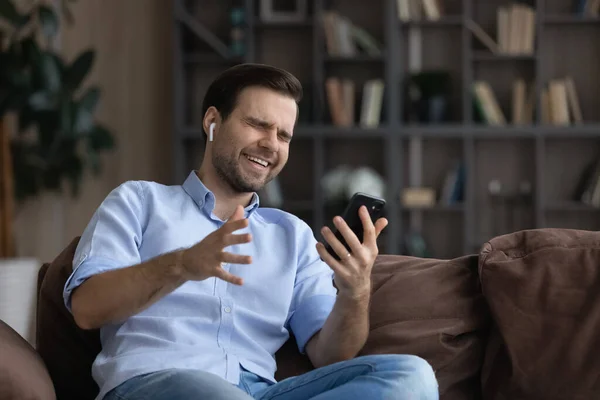 Joven alegre en los auriculares riendo mirando la pantalla del teléfono celular. — Foto de Stock