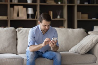 Mutlu milenyum adamı akıllı telefon kullanıyor, kanepede oturuyor..