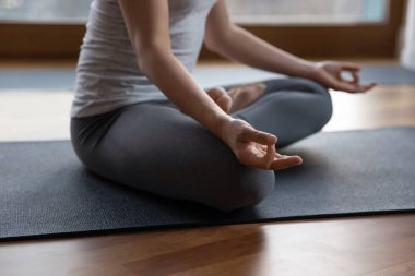 Kesilmiş görüntüyü kapat. Meditasyon yapan kadın. Bacak bacak üstüne atarak evde otur.