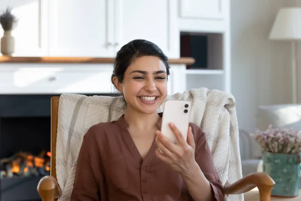 Nadšený indický žena číst sms na smartphone zatímco relaxovat uvnitř — Stock fotografie