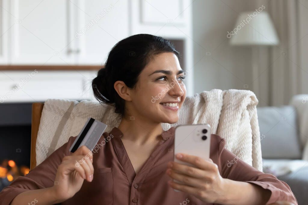 Indian woman holds credit card and smartphone buying goods online
