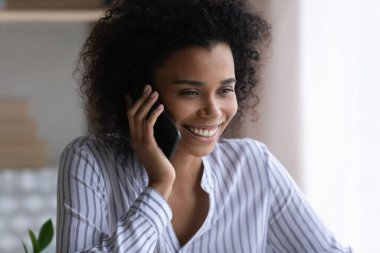 Gülümseyen Afrikalı Amerikalı kadın telefon görüşmesi yapıyor.