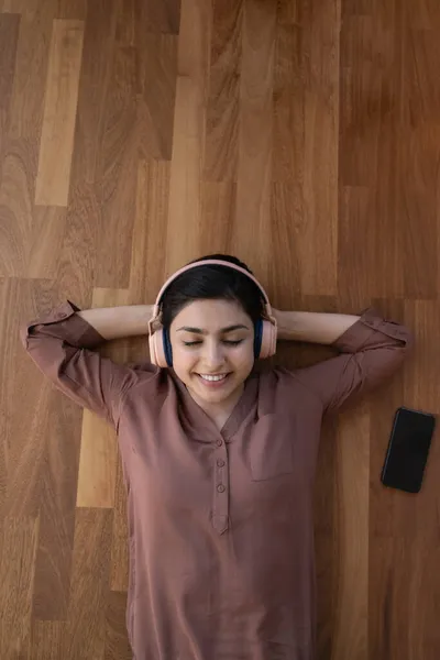 Serene Indian woman lying on floor listen music through headphones — Stock Photo, Image