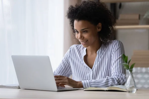 Uśmiechnięta Afroamerykanka pracująca na laptopie online, pisząca — Zdjęcie stockowe