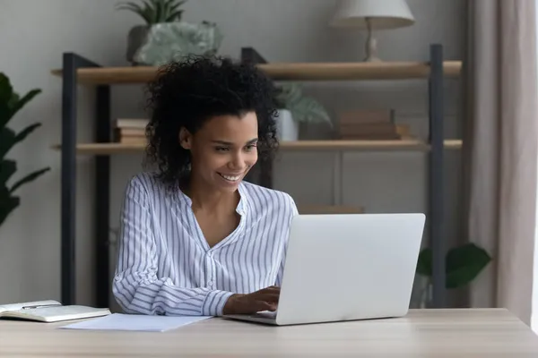 在家里的笔记本电脑上工作的非洲裔美国女人微笑 — 图库照片