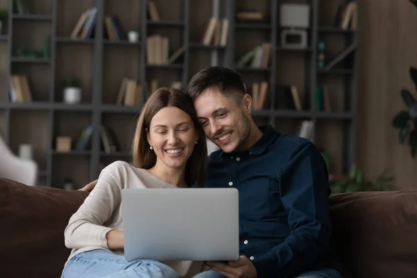 Glückliches kaukasisches Paar nutzt Laptop und entspannt zusammen auf der Couch — Stockfoto