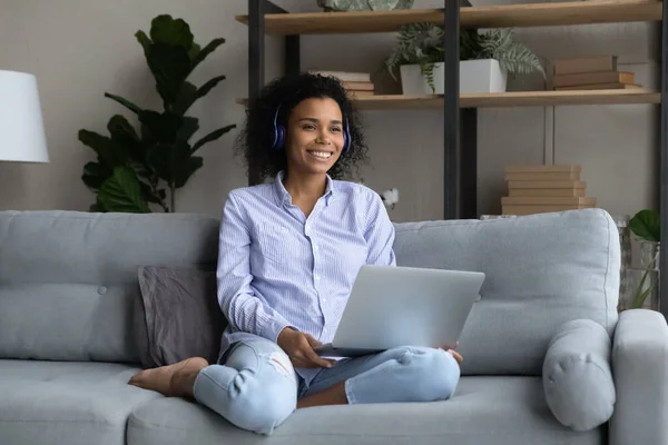 Glimlachende Afro-Amerikaanse vrouw in draadloze koptelefoon kijken in de verte — Stockfoto